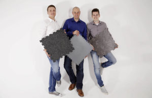 Auf diesem Bild ist das Team von Floorwork mit ihren PVC Bodenplatten in der Hand zu sehen.