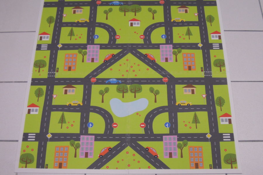 Hier ist ein mit Spielstraßen und Autos bedruckter PVC Bodenfliesen Teppich zu sehen.