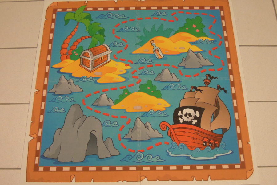 Auf diesem Bild ist eine kleine Spielfläche für Kinder zu sehen. Ein Piratenschiff und Inseln sind auf PVC Bodenfliesen aufgedruckt.