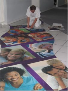Hier verlegt gerade ein Mann einen mit Familienfotos bedruckten PVC Boden.