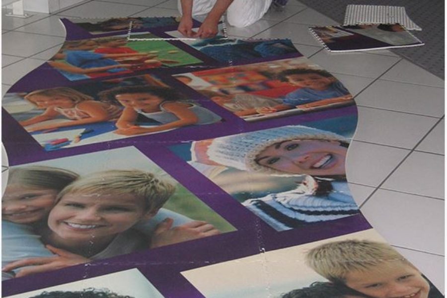 Hier verlegt gerade ein Mann einen mit Familienfotos bedruckten PVC Boden.